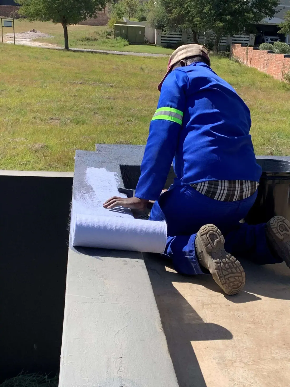 Technician sealing a waterproof membrane around a flat roof parapet and outlet